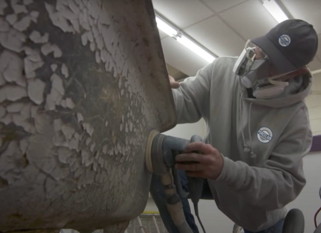 Technician refinishing a bathtub in a Lynn, MA apartment building, carefully applying a new coating for a smooth, long-lasting finish