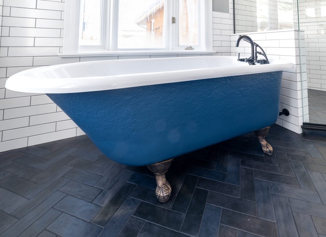 Technician carefully refinishing a bathtub in a Newton, MA single-family home using specialized tools